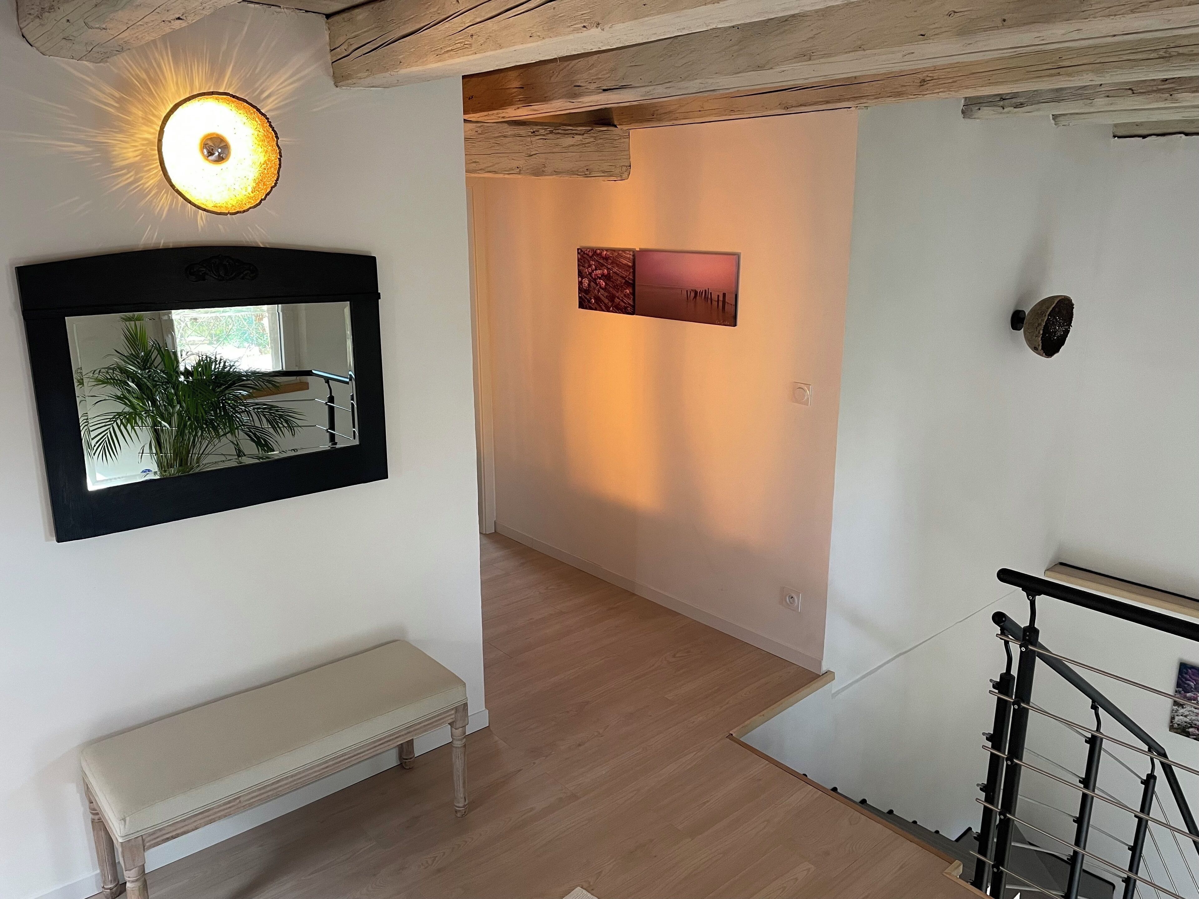 Ein Flur mit einer Bank, einem Wandspiegel, einer Leuchte und einer Treppe.