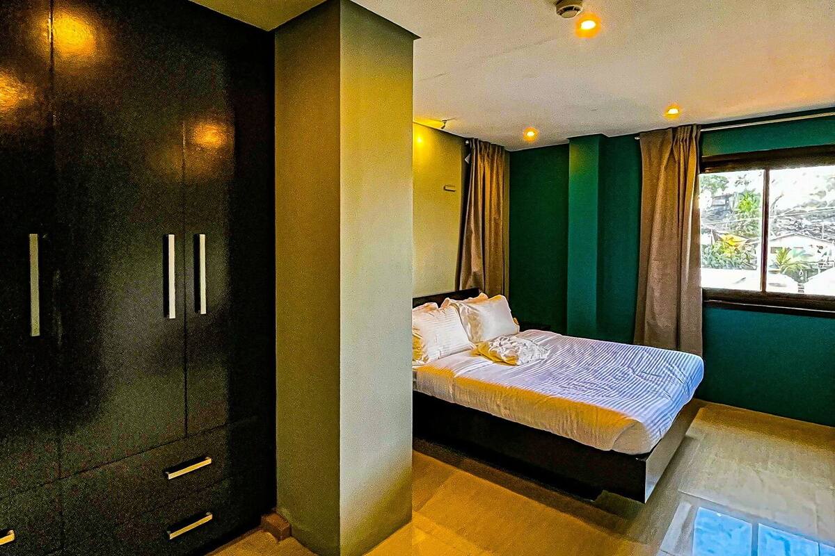 Ein modernes Hotelzimmer mit einem großen Bett, einem Kleiderschrank und Blick ins Freie.