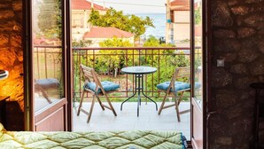 A balcony with two chairs and a small table, overlooking a residential area with houses and trees.