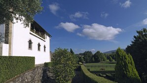 Un edificio blanco con un muro de piedra y un sendero que lleva a un campo verde.