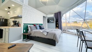 A modern tented accommodation with a bed, kitchenette, and a view of the outdoors. - Cozy and luxurious Emerald Glamping Dome with panoramic views. Fully Accessible (Port Wade)