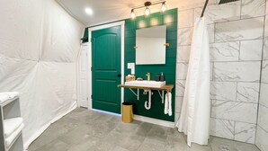 A bathroom with a green door, a white sink with a mirror, and a shower curtain. - Cozy and luxurious Emerald Glamping Dome with panoramic views. Fully Accessible (Port Wade)