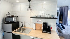 A compact kitchen with a microwave, coffee maker, and a small sink. - Cozy and luxurious Emerald Glamping Dome with panoramic views. Fully Accessible (Port Wade)