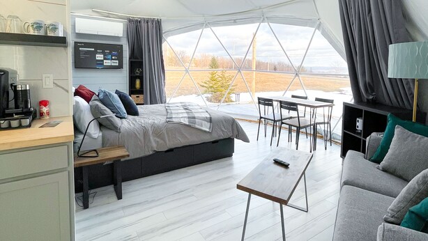 A spacious tent with a bed, seating area, and a kitchenette. - Cozy and luxurious Emerald Glamping Dome with panoramic views. Fully Accessible (Port Wade)