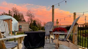 A wooden deck with Adirondack chairs, a covered table, and a small shed. - Cozy and luxurious Emerald Glamping Dome with panoramic views. Fully Accessible (Port Wade)