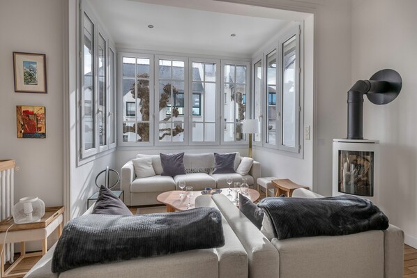 A modern living room with a large window, a sofa set, a coffee table, and a lamp.