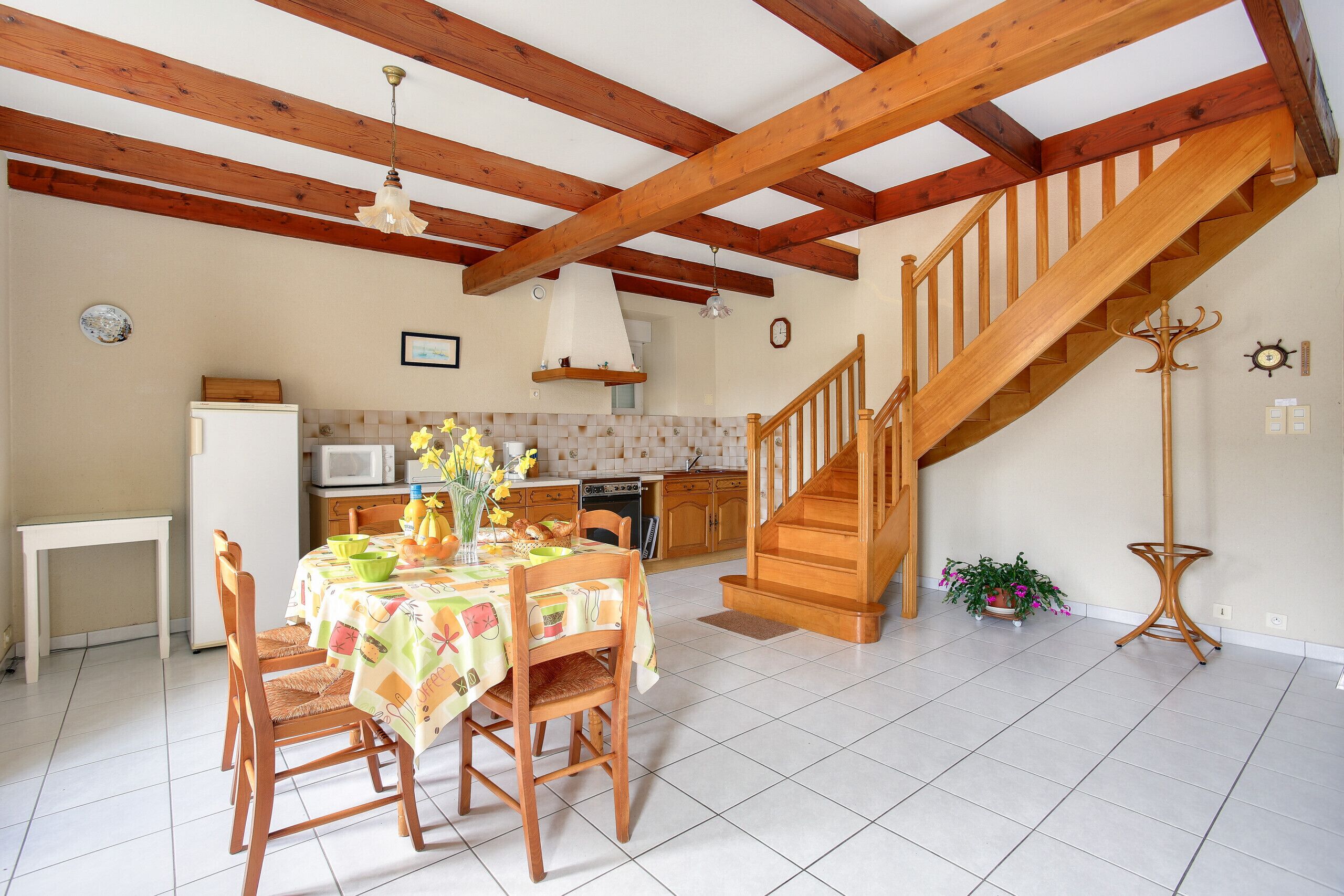 Una cocina con una mesa de comedor, sillas, microondas y una escalera.