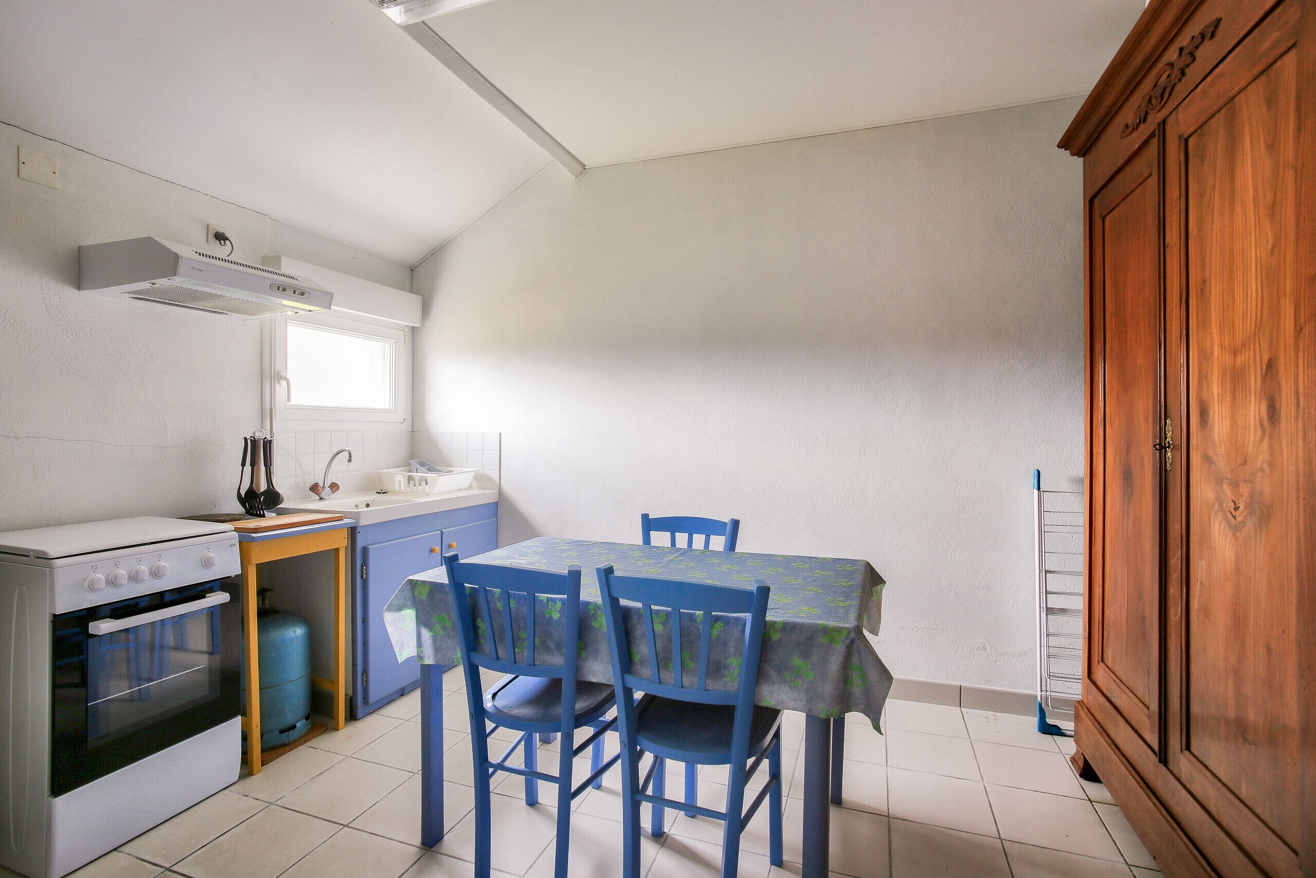 A compact kitchen with a stove, sink, and wooden cabinet.