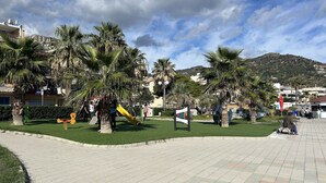 A park with palm trees, a playground, and a paved area.