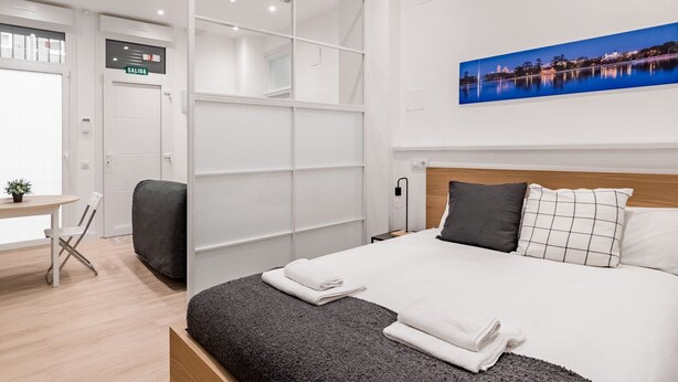A modern hotel room with a bed, a desk, and a large wardrobe. - GuestReady - Flat near Palacio Real (Madrid)