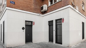A building with two black doors, a fire alarm, and a sign for "Calle de Pizarra". - GuestReady - Flat near Palacio Real (Madrid)