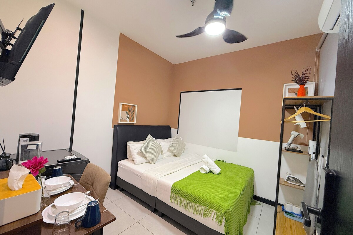 A bedroom with a bed, bedside table, desk, chair, wardrobe, and ceiling fan.