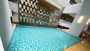 A swimming pool with a tiled floor and a wooden deck surrounding it. - Neu Suites By Serenity Vacation Homes (Kuala Lumpur)