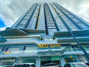 A high-rise building with multiple balconies and a sign for 'NEU SUITES'.