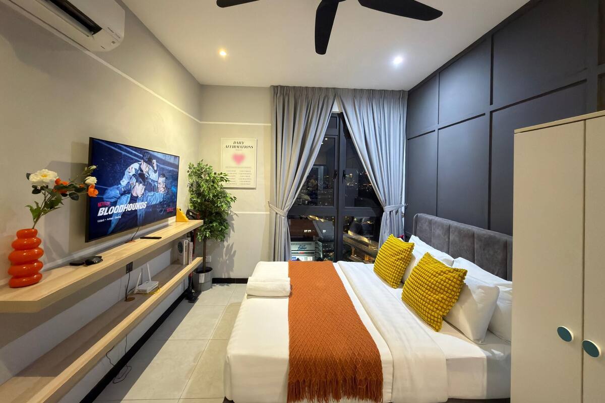 A modern hotel room with a bed, TV, and a city view.
