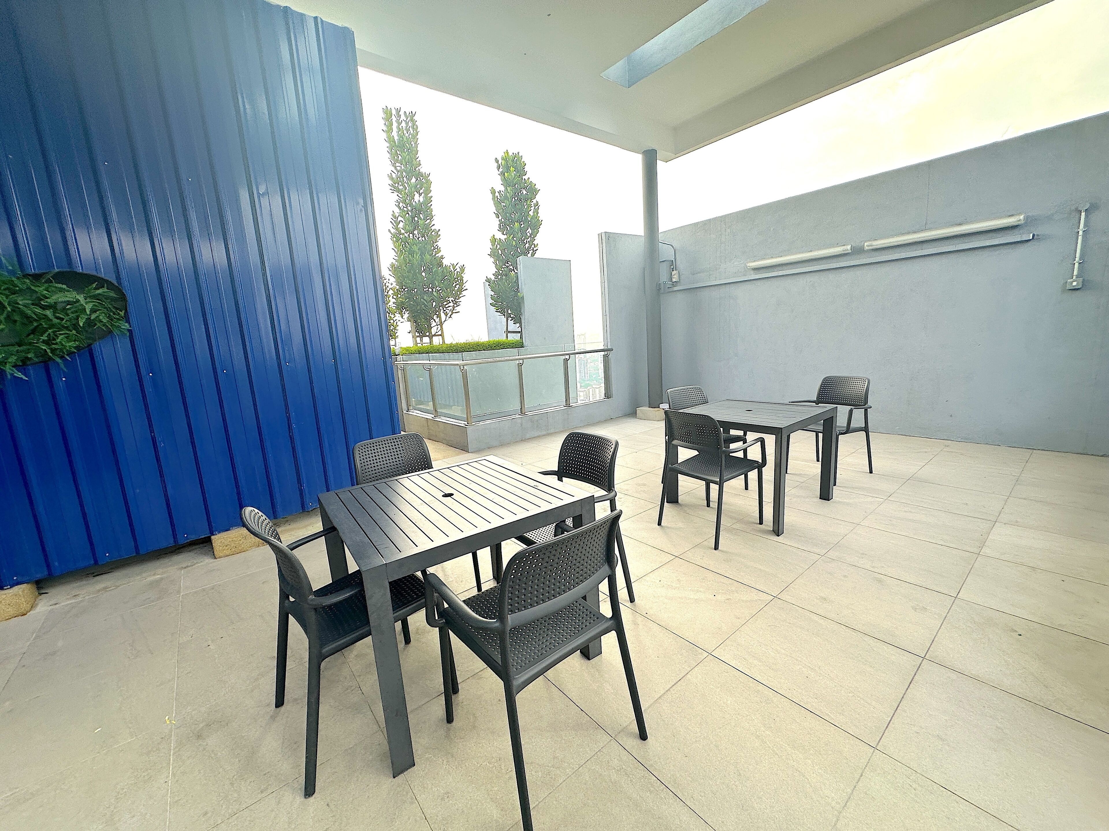 An outdoor patio area with a blue wall, a table with chairs, and a railing.