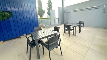 An outdoor patio area with a blue wall, a table with chairs, and a railing.