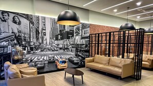 A modern interior with a cityscape mural, leather sofas, and a black partition. - Neu Suites By Serenity Vacation Homes (Kuala Lumpur)