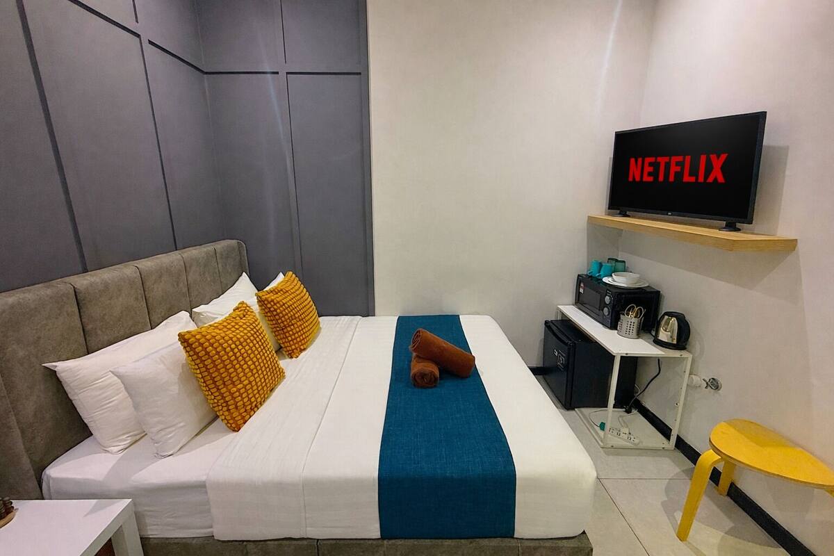 A hotel room with a bed, a TV, a small table, and a microwave.