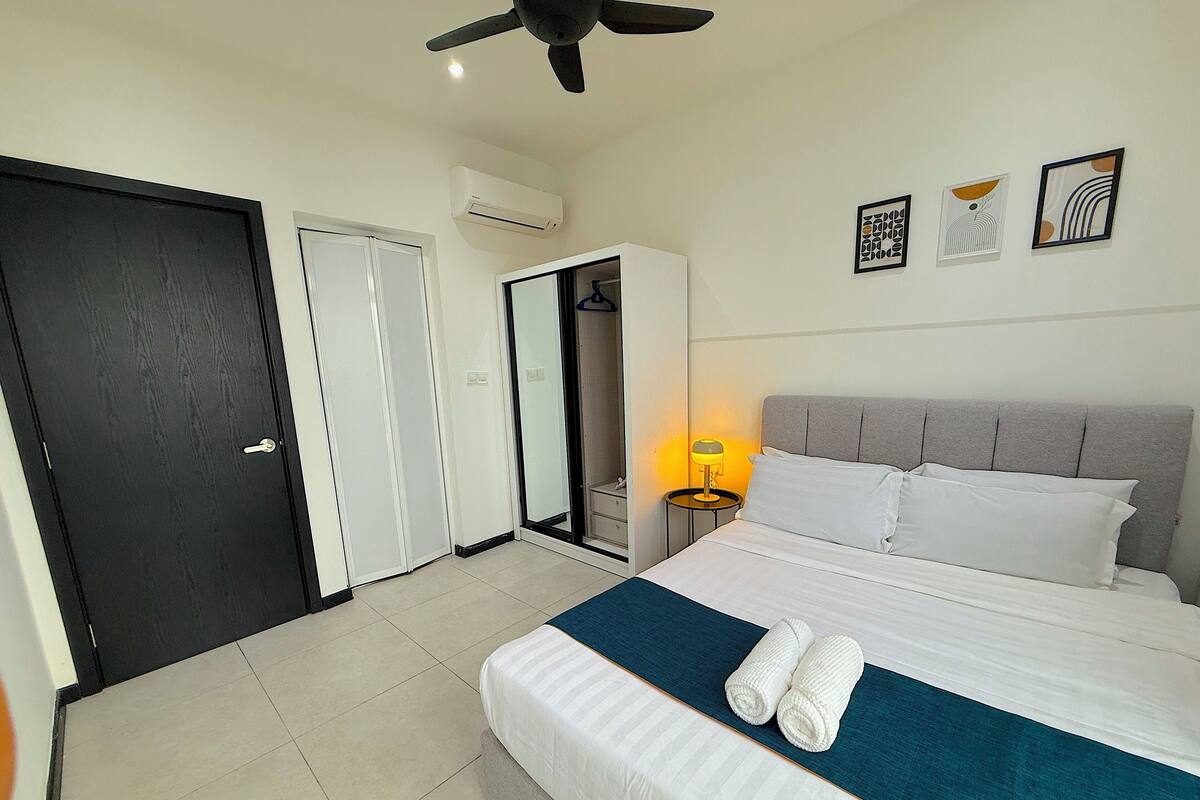 A hotel room with a bed, a ceiling fan, a wardrobe, a mirror, and wall art.
