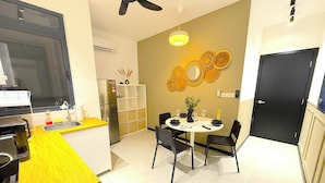A compact kitchen with a refrigerator, sink, and a dining area with a table and chairs.