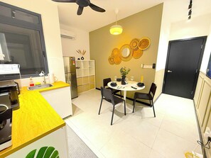 A compact kitchen with a refrigerator, sink, and a dining area with a table and chairs.