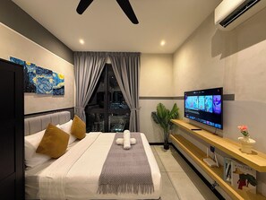 A modern hotel room with a bed, a TV, a plant, and a city view.