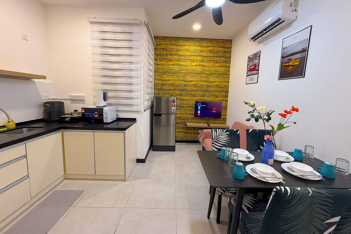 A modern kitchen with a built-in oven, a refrigerator, and a dining area with a table set for two.