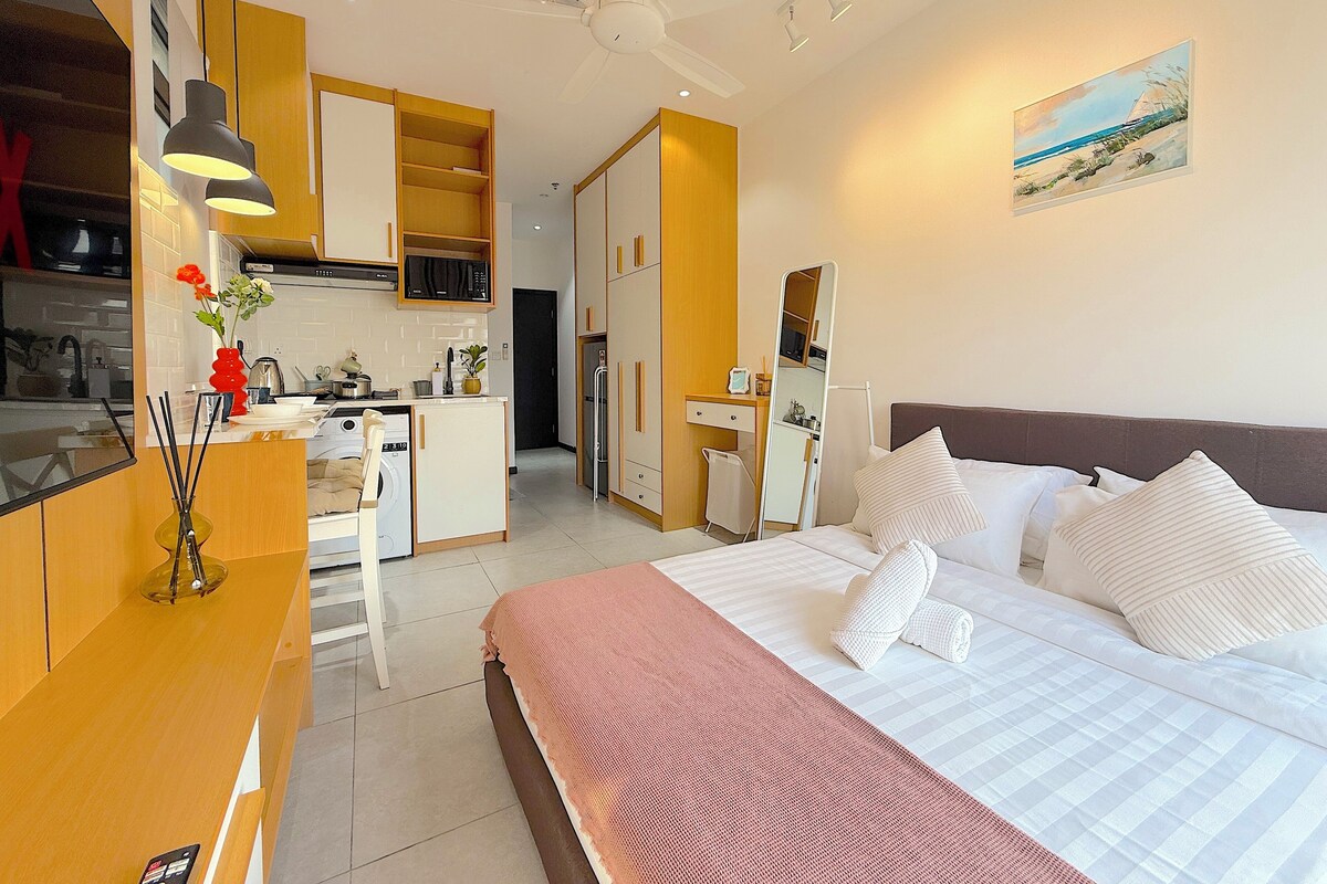 A modern hotel room with a bed, bedside table, and a view of the beach.