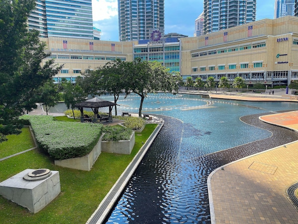 A modern urban setting with a central water feature, surrounded by greenery and modern buildings.
