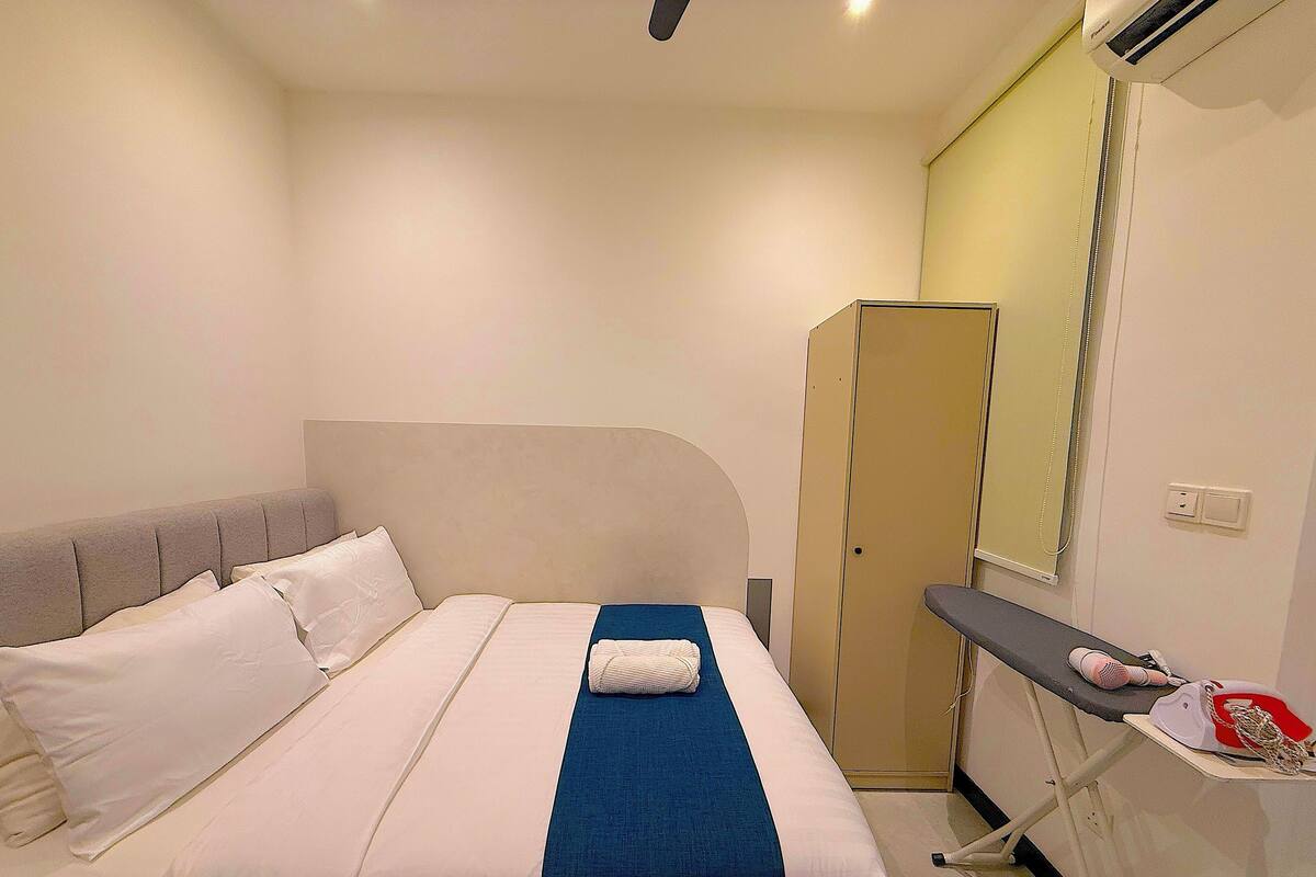 A hotel room with a bed, a wardrobe, and a small ironing board with an iron.