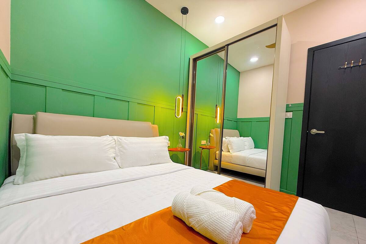 A hotel room with a bed, a bathroom mirror, and a door.
