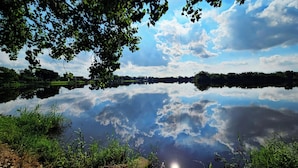 En stilla sjö med tydliga speglingar av himlen och de omgivande träden.