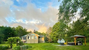 Ein Haus mit großem Garten, einer überdachten Sitzgelegenheit und einem kleinen Pavillon.