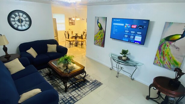 A living room with a sofa, coffee table, and a TV mounted on the wall. - “Cozy Diamond on the Corner” (Port Arthur)