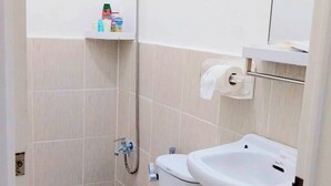 Ein kleines, kompaktes Badezimmer mit Toilette, Waschbecken und Dusche.