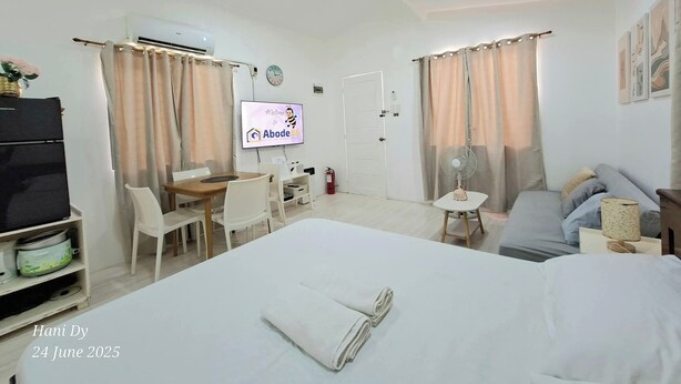 Ein Hotelzimmer mit Bett, Schreibtisch, Stuhl, Fernseher und Ventilator.