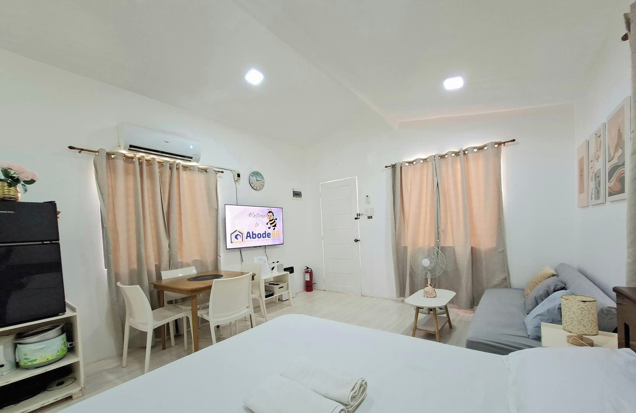 A hotel room with a bed, a desk, a chair, a TV, and a fan.