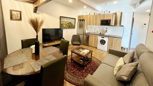Uma sala de estar moderna com uma mesa de jantar, sofá e área de cozinha com armários de madeira e eletrodomésticos.