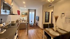 A modern hotel room with a kitchenette, a dining area, and a living space. - Casón De Los López Apartments 1B (Toledo)