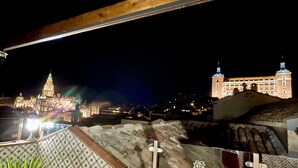 Yökuva historiallisesta rakennuksesta, jossa on valaistut tornit ja suuri kupoli, näkymä on otettu parvekkeelta, jonka lattialla on kuvioituja laattoja.