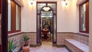 Um corredor com chão de azulejos, um vaso de planta e um banco.