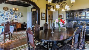 A dining area with a large wooden table, ornate chairs, and a chandelier. - Quinta Lusitânia (Santa Comba Dao)