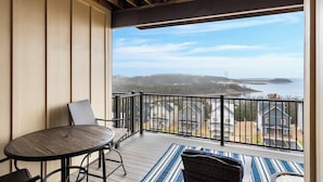 A balcony with a wooden table and chairs, a view of a residential area and a body of water. - Majestic Lakeview Destination Unmatched Location (Branson)