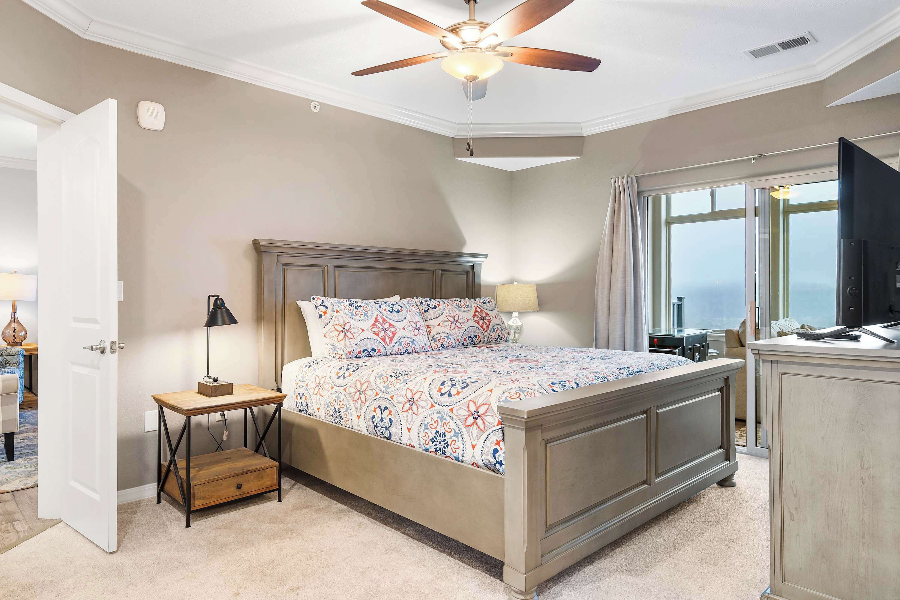 A bedroom with a bed, bedside table, lamp, and a ceiling fan.