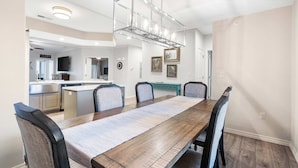 A dining area with a long wooden table, six chairs, and a modern chandelier. - Majestic Lakeview Destination Unmatched Location (Branson)