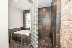 Un bagno con una vasca, un box doccia in vetro e una parete in mattoni.