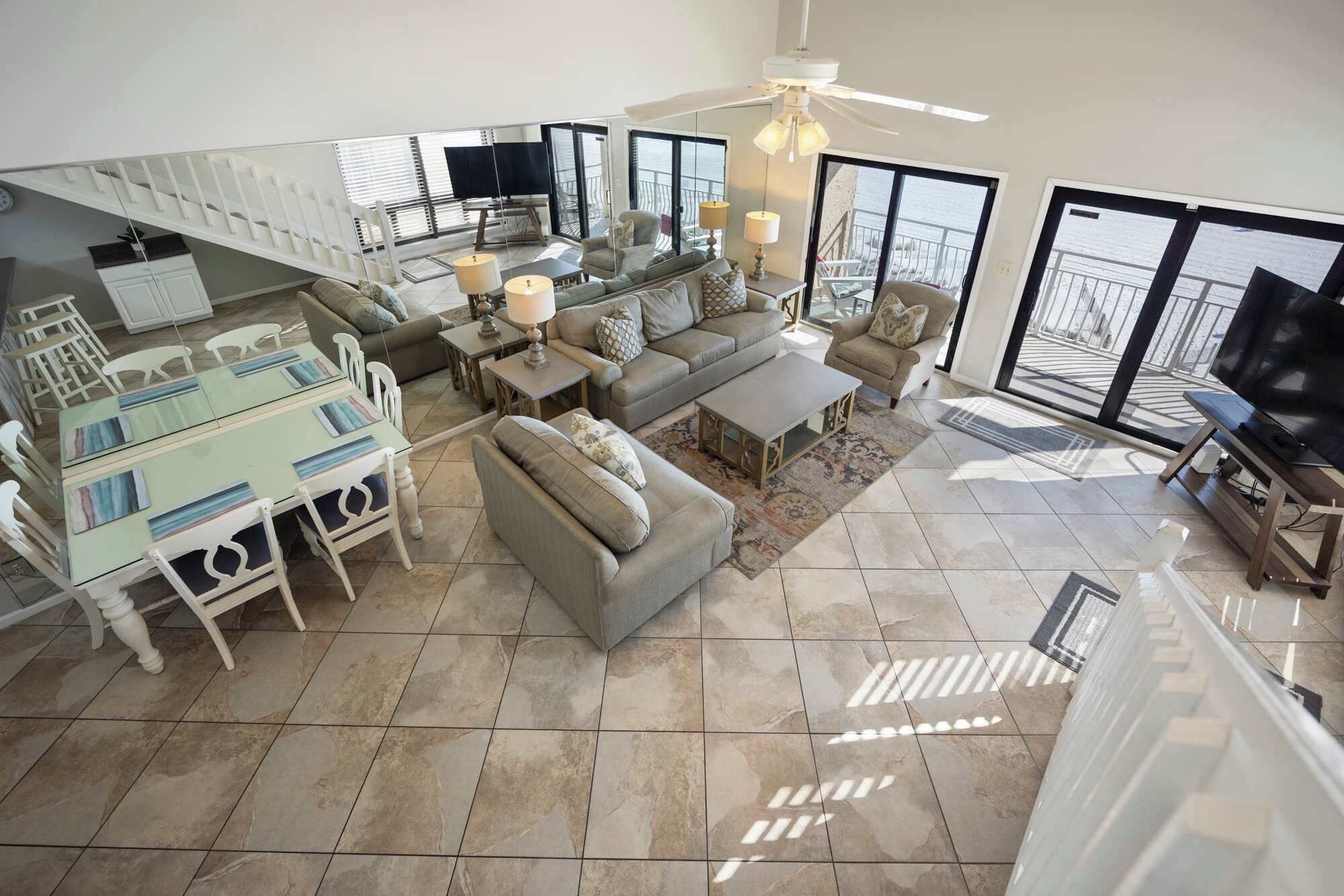 A spacious living area with a balcony, a dining table with chairs, a sofa, and a television.