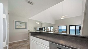A modern kitchen with a granite countertop, white cabinetry, and a built-in dishwasher. - Gulf View Getaway at Crystal Villas (Destin)