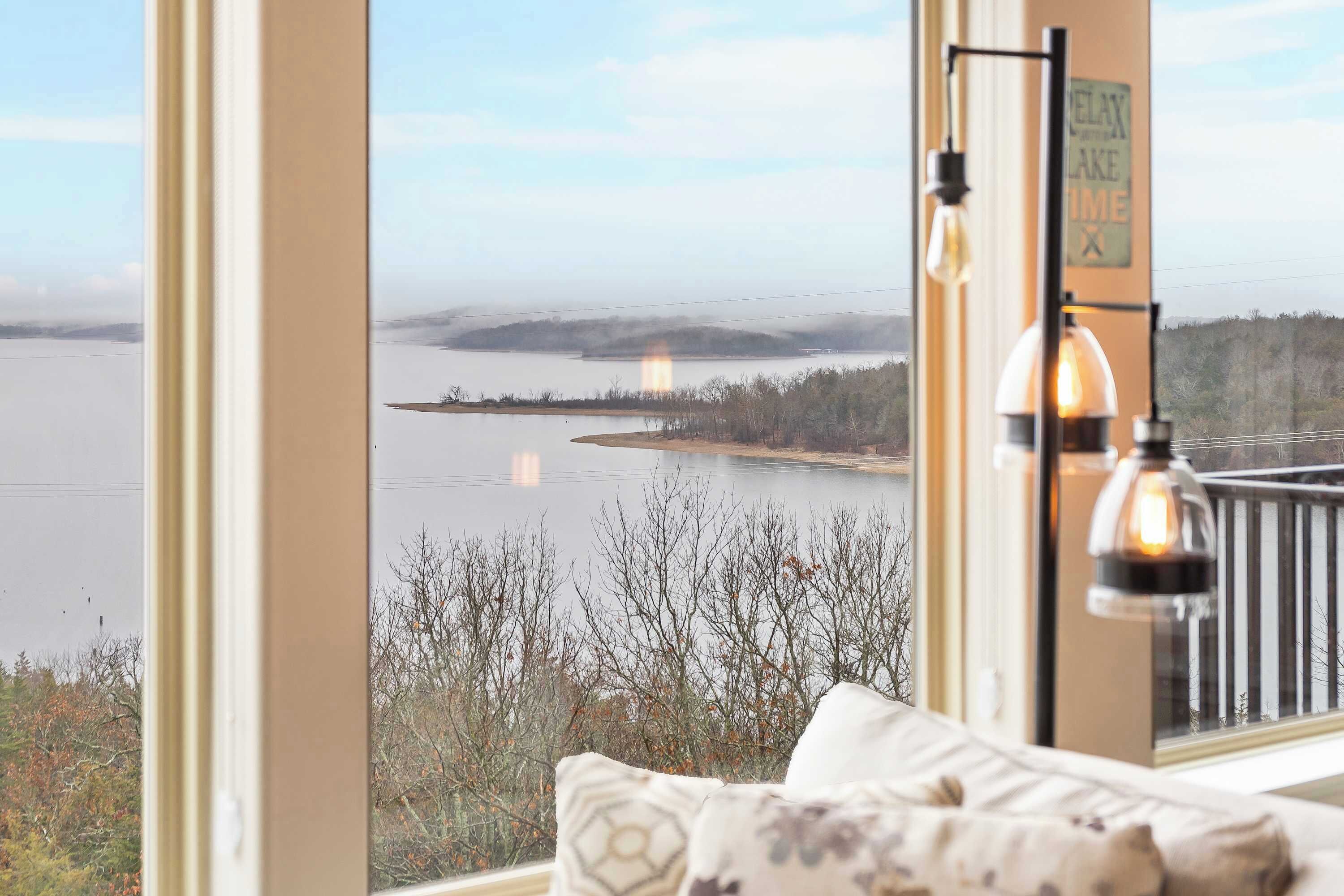 Una habitación con un ventanal grande que da a un lago, vistas del lago, y un cartel que dice 'Relax Lake Time'.